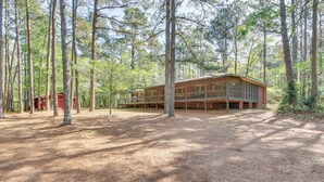 Una cabaña en un bosque con una amplia terraza y varias ventanas.