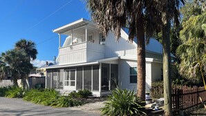 A two-story house with a covered porch, a fenced yard, and palm trees. - St. Marys Chic: Porch Living & Total Walkability! (St. Marys)