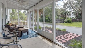 A covered porch with wicker furniture and a view of the street and greenery. - St. Marys Chic: Porch Living & Total Walkability! (St. Marys)