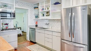 A modern kitchen with white cabinetry, a stainless steel refrigerator, a microwave, and a sink. - St. Marys Chic: Porch Living & Total Walkability! (St. Marys)
