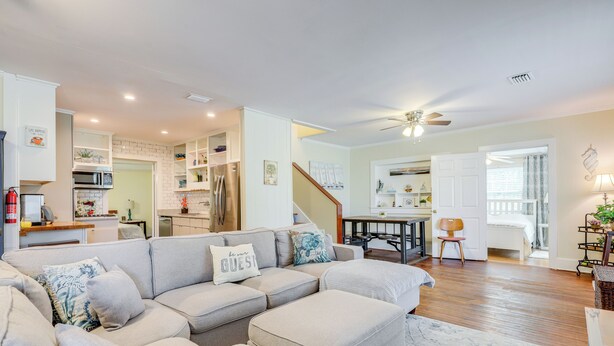 A modern living room with a sectional sofa, a dining area, and a kitchen in the background. - St. Marys Chic: Porch Living & Total Walkability! (St. Marys)