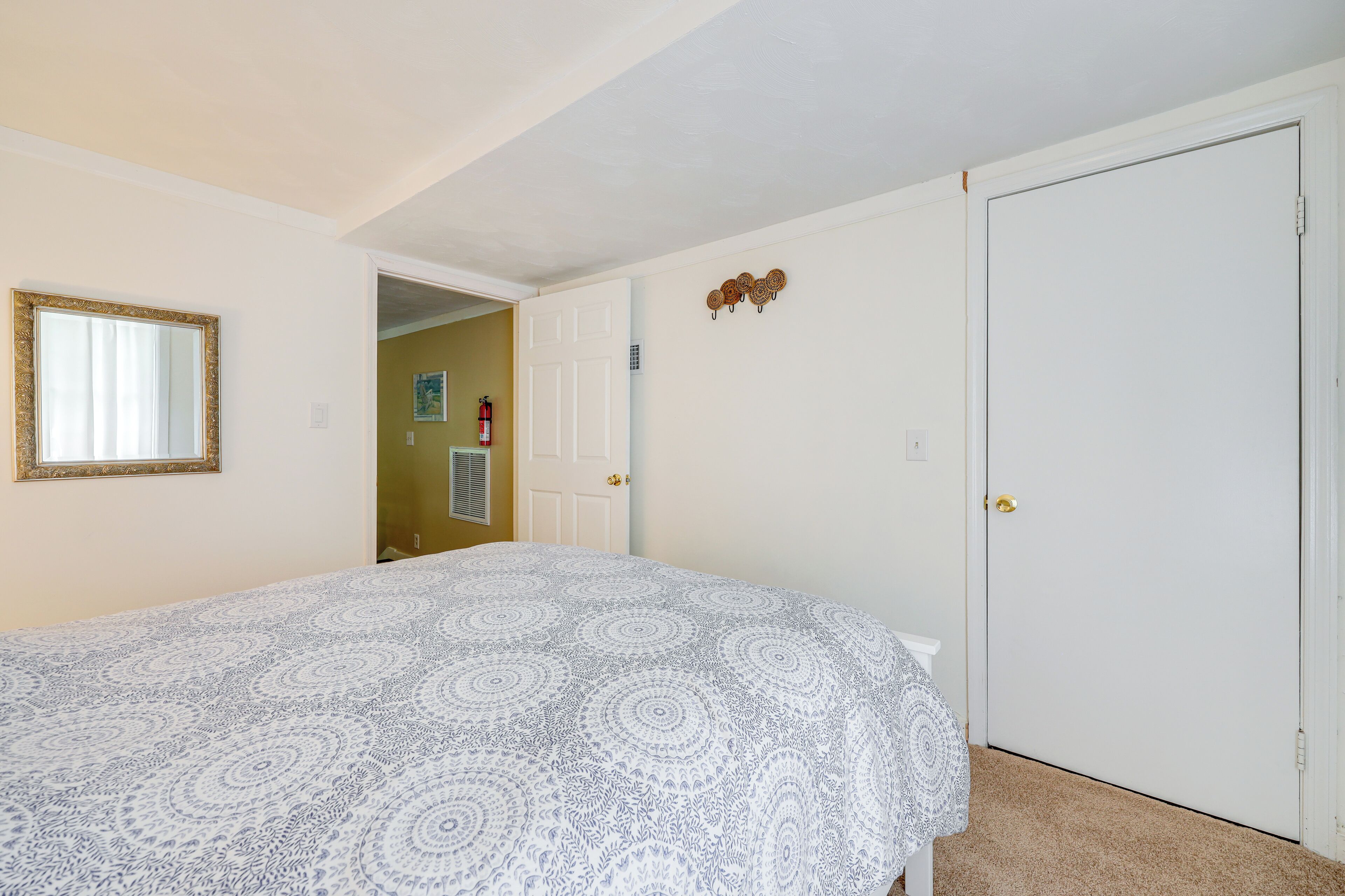 A bedroom with a bed, a door, and a mirror.