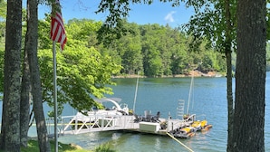 A dock with a small boat, surrounded by trees and a clear lake.