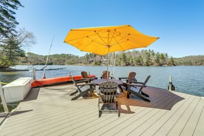 A wooden deck with outdoor furniture, including chairs and a table, overlooking a body of water. - Mtn-view Home on Lake Glenville w/ Dock (Cashiers)