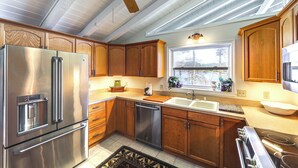 A kitchen with wooden cabinets, stainless steel appliances, a dishwasher, and a window with a view.