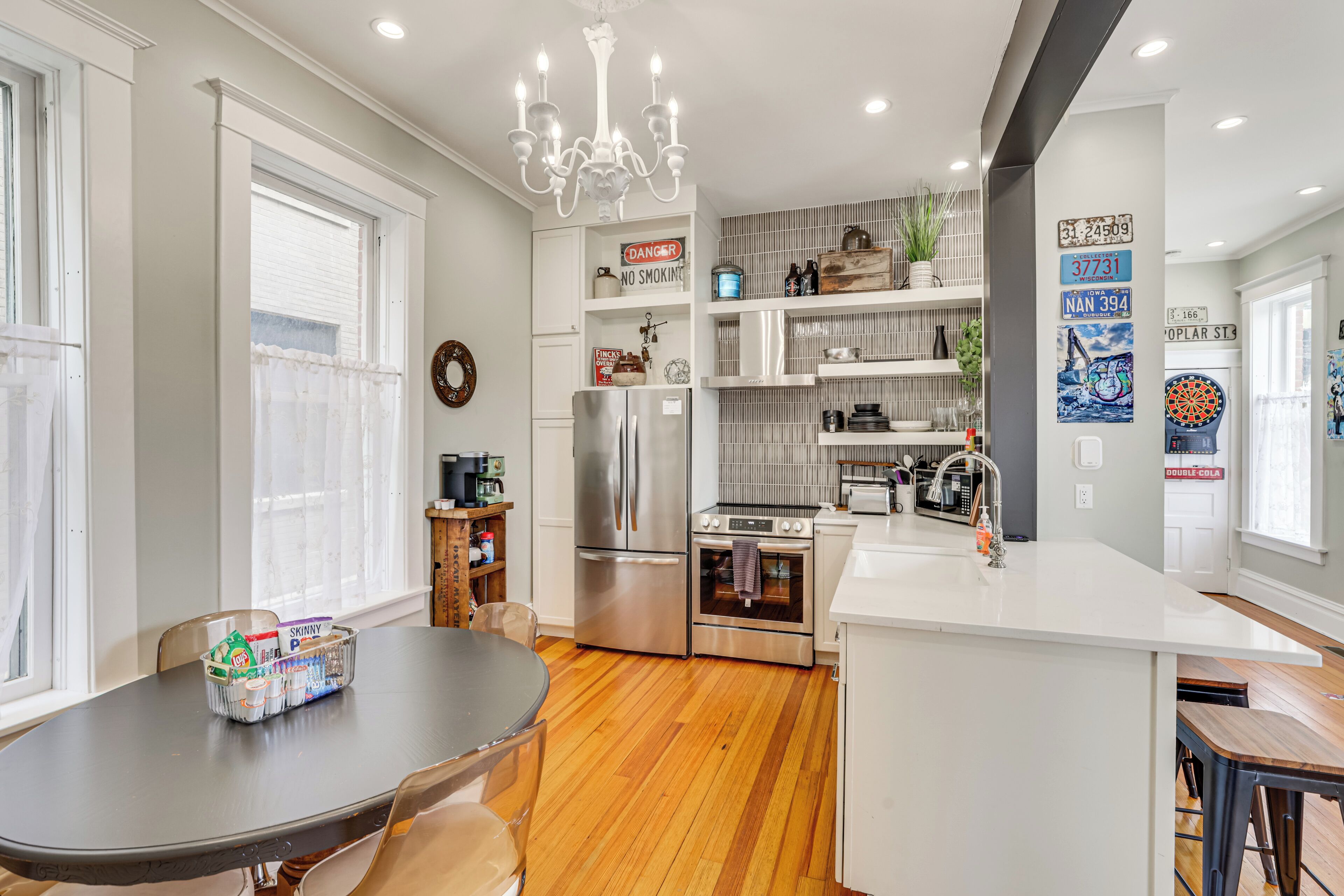 A modern kitchen with a central island, stainless steel appliances, and a chandelier.