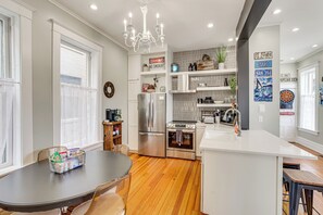 A modern kitchen with a central island, stainless steel appliances, and a chandelier.