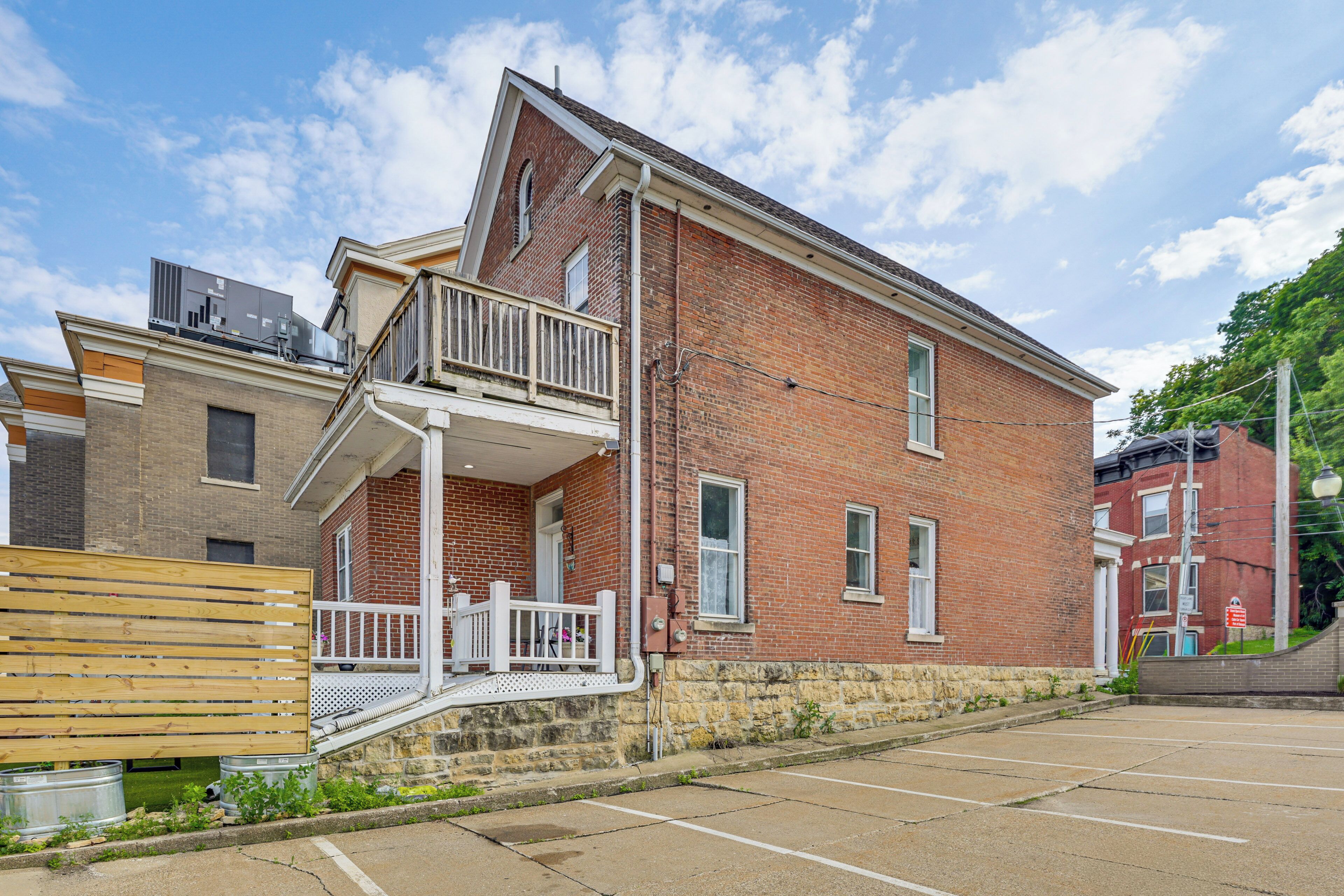 A two-story brick building with a balcony, a wooden bench, and a parking lot.
