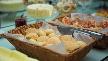 Un bufé con diferentes opciones de comida, incluyendo pan, bollería y postres.