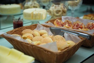 Un bufé con diferentes opciones de comida, incluyendo pan, bollería y postres.