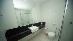 A modern bathroom with a black countertop, white sink, and a glass shower enclosure.