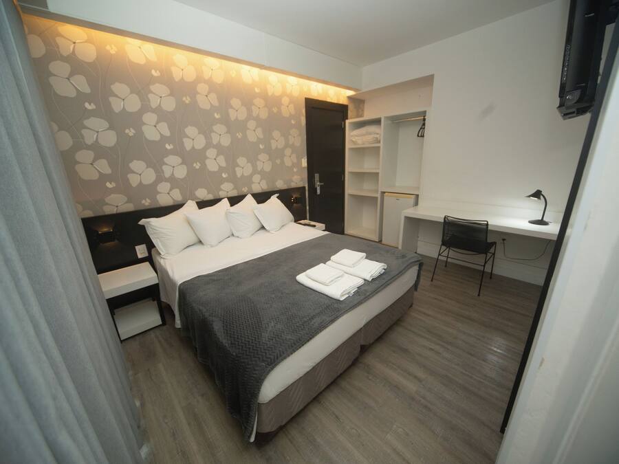 Una habitación de hotel moderna con cama, mesitas de noche, un escritorio y una silla.
