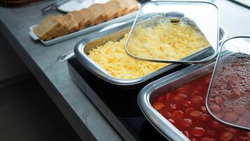 Un bufé con fuentes de huevos revueltos, frijoles y pan.
