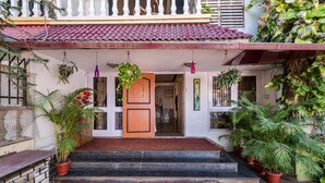 A traditional house with a wooden door, steps leading to a porch, and potted plants.