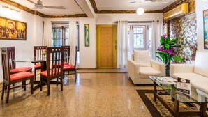A spacious living room with a glass coffee table, a sofa, and a dining area with chairs.