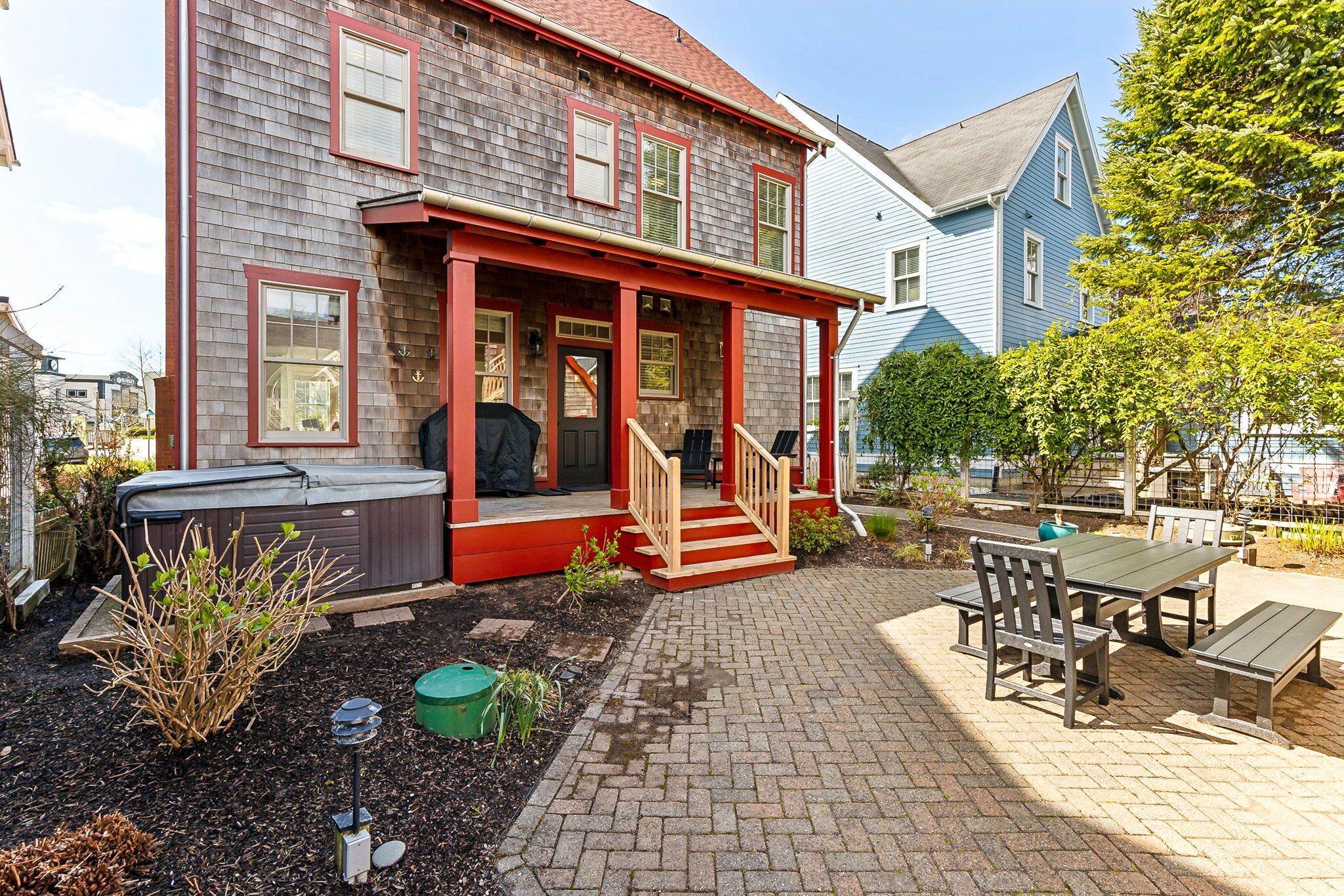 A two-story house with a porch, outdoor seating, and a hot tub.