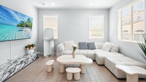 A modern living room with a sectional sofa, a round coffee table, and a flat-screen TV mounted on the wall. - Modern Spacious Home Bright Family Group Friendly (La Puente)