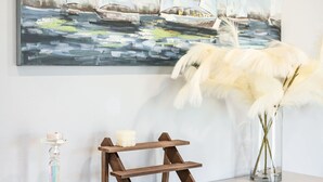 A white cabinet with a painting of sailboats, a candle holder, and pampas grass. - Modern Spacious Home Bright Family Group Friendly (La Puente)