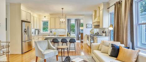 A modern kitchen with a dining area, a sofa with cushions, and a view of the outdoors.