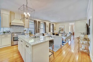 A modern kitchen with a central island, stainless steel appliances, and a dining area with a sofa and table.
