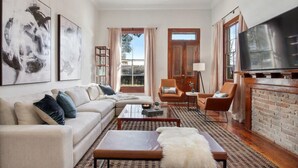 Un salon moderne avec un canapé, une table basse et des fauteuils, une cheminée et un grand téléviseur.