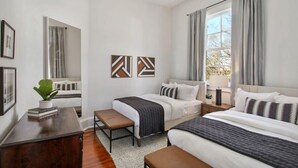 Une chambre moderne avec deux lits, un bureau et une grande fenĂŞtre avec des rideaux.