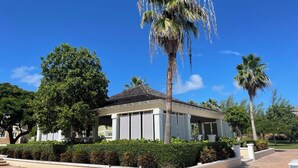 Un bâtiment à deux étages doté d’un patio couvert, entouré d’un aménagement paysager soigné et de palmiers.