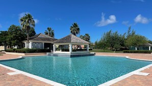 Une piscine avec un kiosque et des palmiers en arrière-plan.