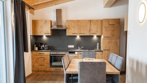 Una cocina moderna con armarios de madera, una isla central y una zona de comedor con sillas.
