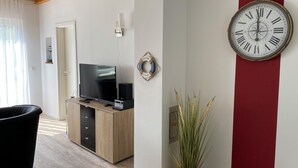 A modern living room with a TV, speakers, and a plant.