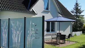 A house with a tiled roof, a window, and a patio with a table and chairs.