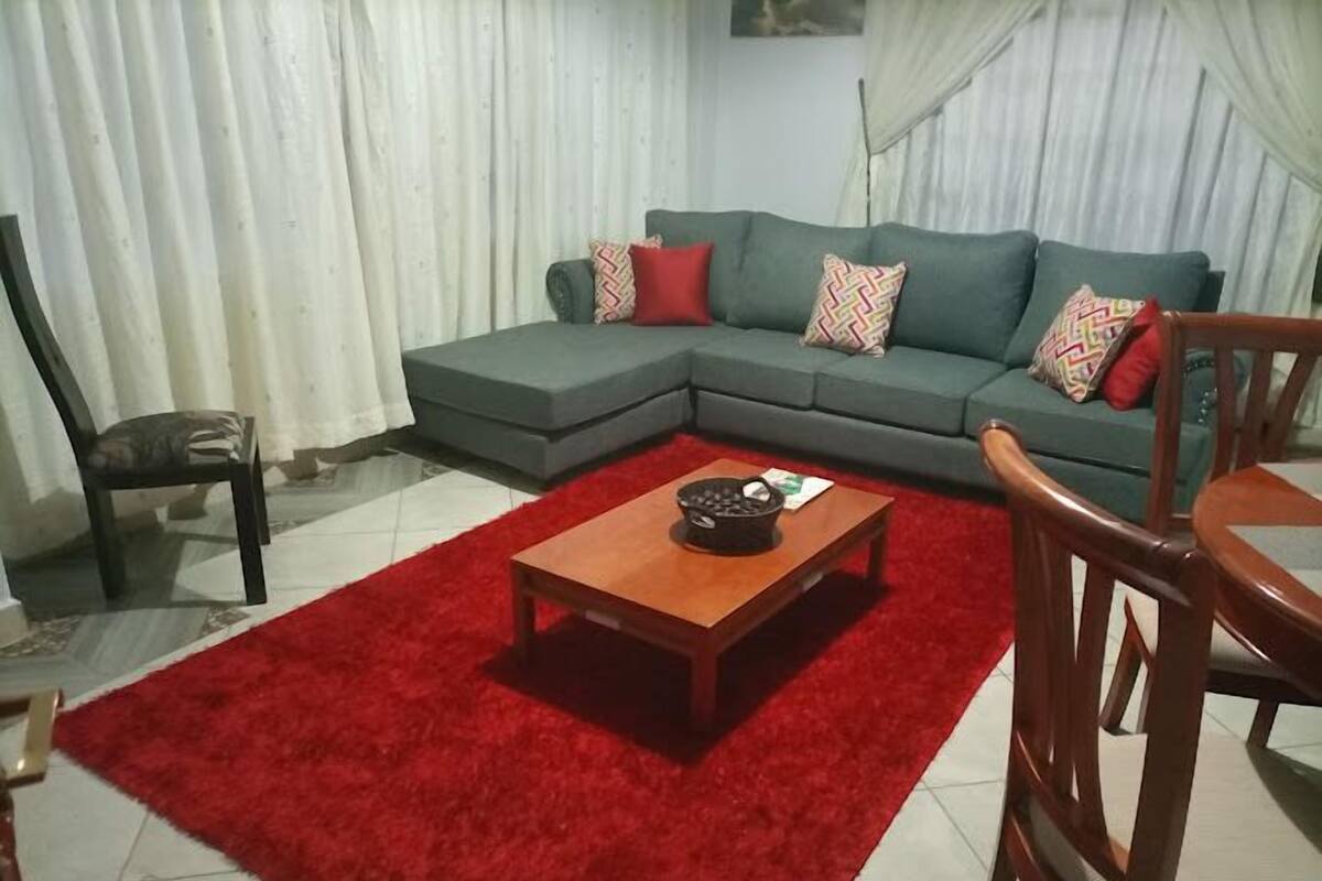 Una sala de estar con un sofá modular, una mesa de centro de madera y una alfombra roja.