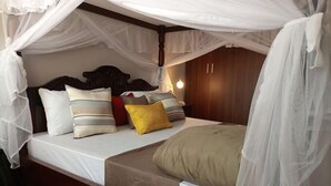 Ein Himmelbett mit Kissen und einem Nachttisch mit Lampe.