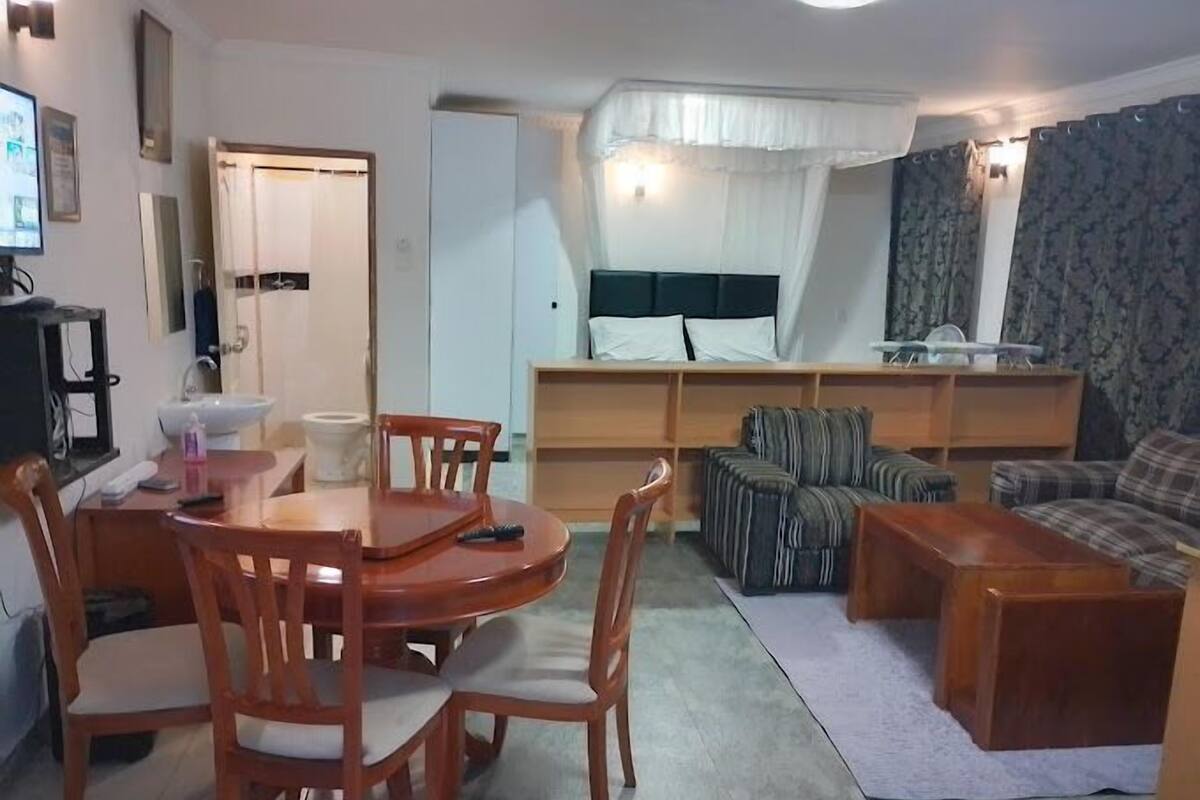 Una sala compacta con una mesa de comedor, sillas, un sofá y un televisor.