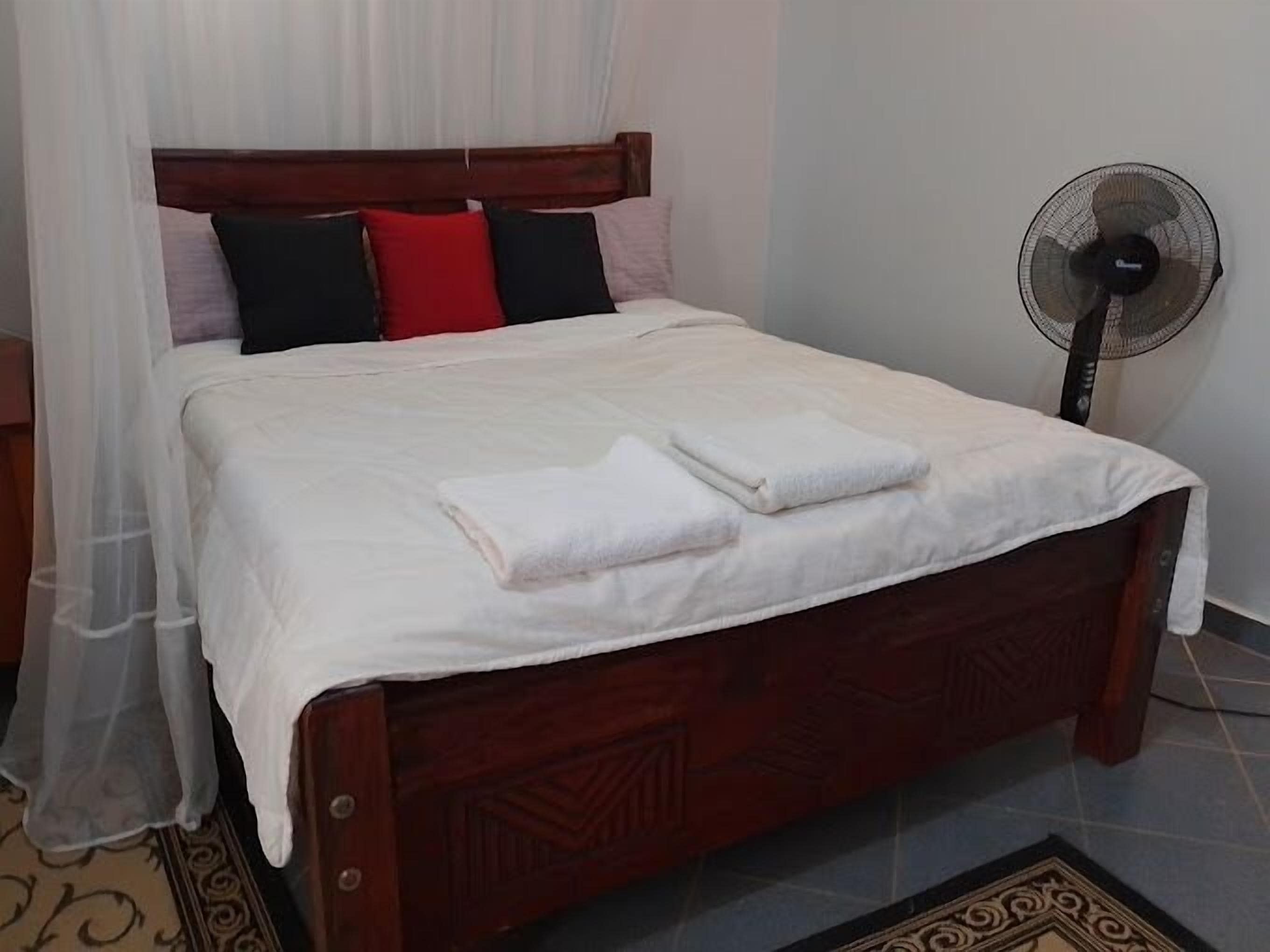 A neatly made bed with white bedding, a wooden headboard, and a bedside table with a lamp.