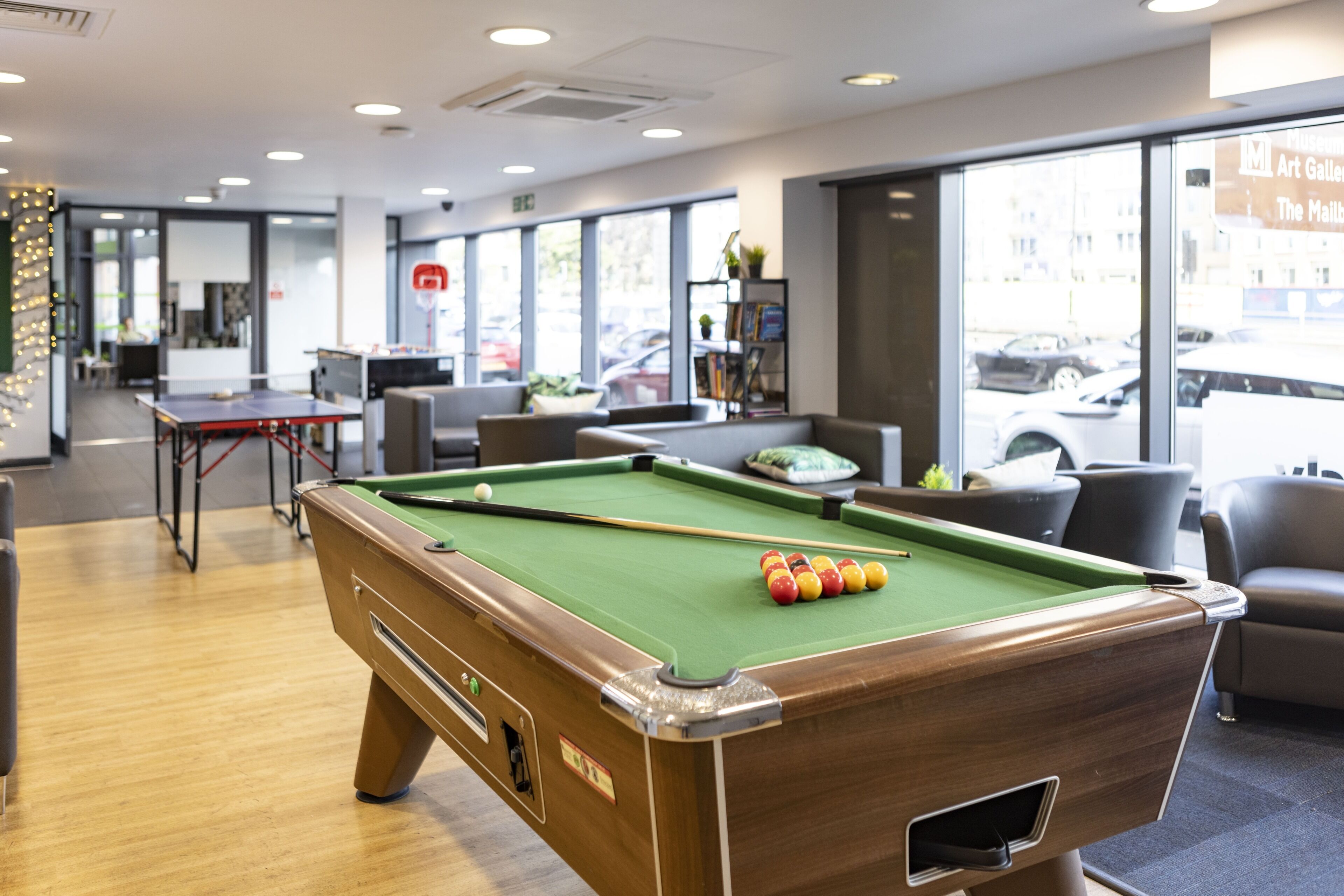 A pool table with balls, a billiards cue, and a green felt surface.