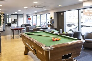 Une table de billard avec des billes, une queue de billard et un tapis vert.