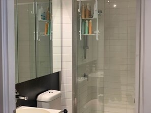 A modern bathroom with a glass shower enclosure, a white sink, and a mirror above the sink. - Beautiful and Convenient apartment in CBD (Melbourne)