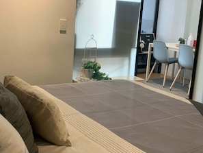A modern room with a sofa, a small table with a plant, and a desk with a chair.