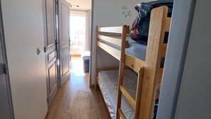 A narrow hallway with wooden flooring leading to a room with bunk beds and a door. - Charming studio cabin in the heart of Font Romeu (font romeu)