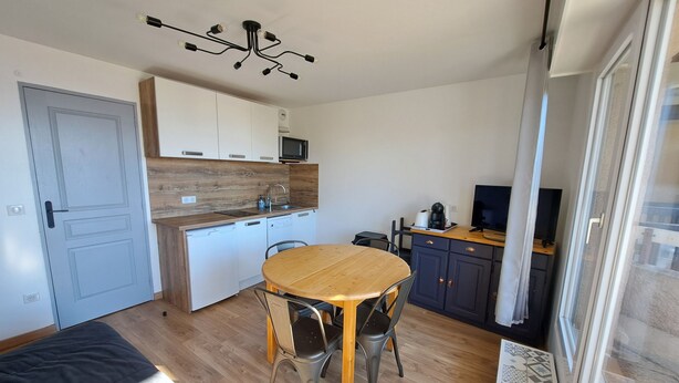 A compact kitchen with a dining area, a microwave, a coffee maker, and a TV on a wooden counter. - Charming studio cabin in the heart of Font Romeu (font romeu)