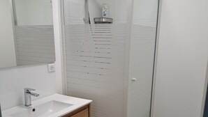 A modern bathroom with a glass-enclosed shower, a white sink, and a mirror. - Charming studio cabin in the heart of Font Romeu (font romeu)