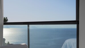 A bedroom with a large window overlooking a body of water and distant mountains. - Oliva Mare (Turunc)