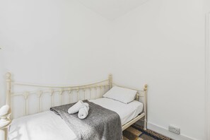 A single bed with a headboard, white bedding, and a grey blanket. - Rustic 2-Bed Home + Garden (Greater London)