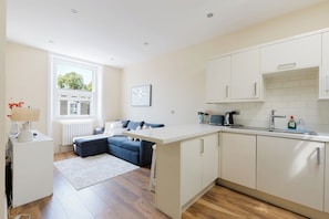 A modern kitchen with white cabinetry, a built-in oven, and a window overlooking a street.