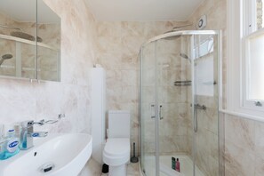 Une salle de bain moderne avec une douche à parois de verre, un lavabo blanc et des toilettes.