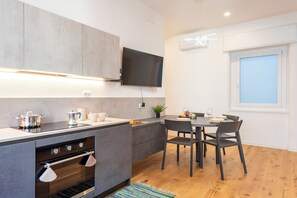 Een moderne keuken met een inbouwoven, een eettafel met stoelen en een wandgemonteerde flatscreen-televisie.