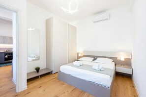 A modern hotel room with a bed, bedside tables, a mirror, and a small plant. - Central Apartment Piazza Dante Genova (Genoa)