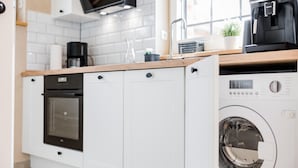Una cocina compacta con horno integrado, cafetera y lavadora.