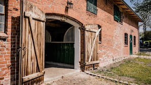 Un edificio de ladrillo con dos grandes puertas de madera y un ventanal verde.